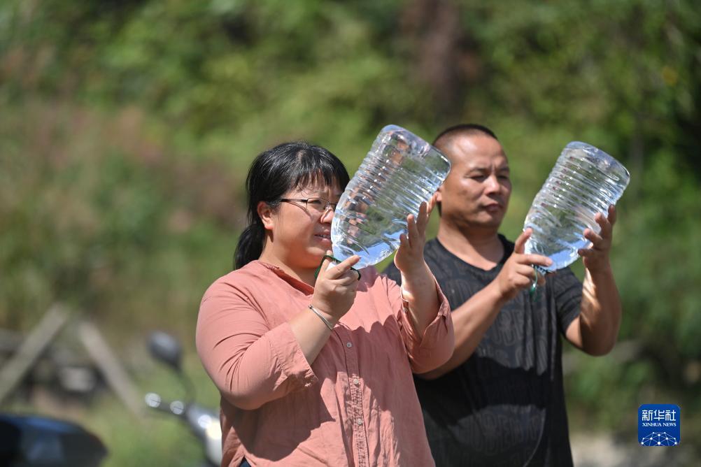 楊寧（左）在查看村民剛剛采集的水樣，為山泉水引水工程做準(zhǔn)備（10月8日攝）。新華社記者 黃孝邦 攝